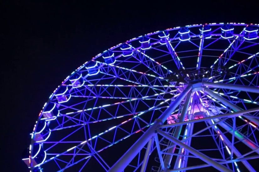 Ferris wheel in blue neon light on dark background, Part of Ferris wheel  with blue illumination against a black sky background at night.
