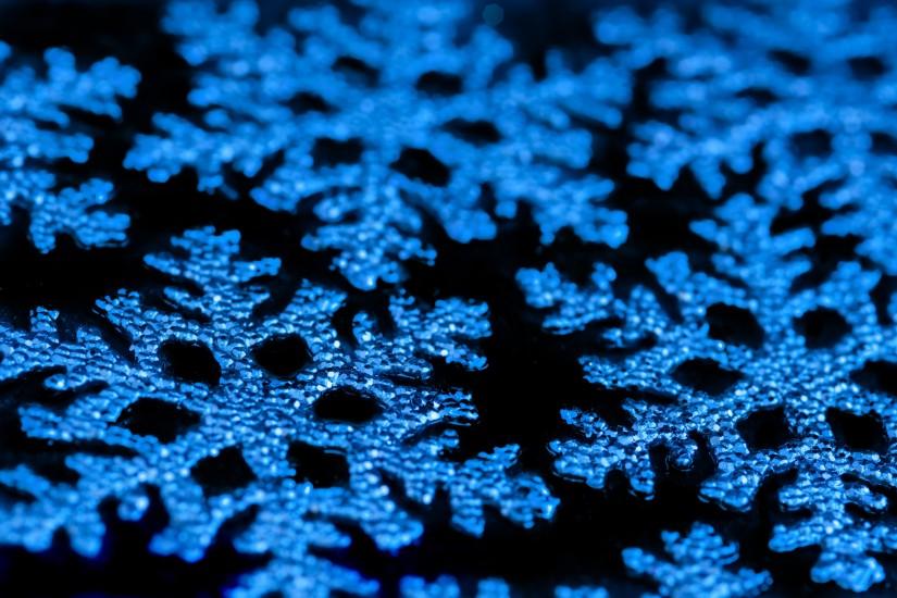 a background photos of blue christmas snowflake ornaments on a black  background