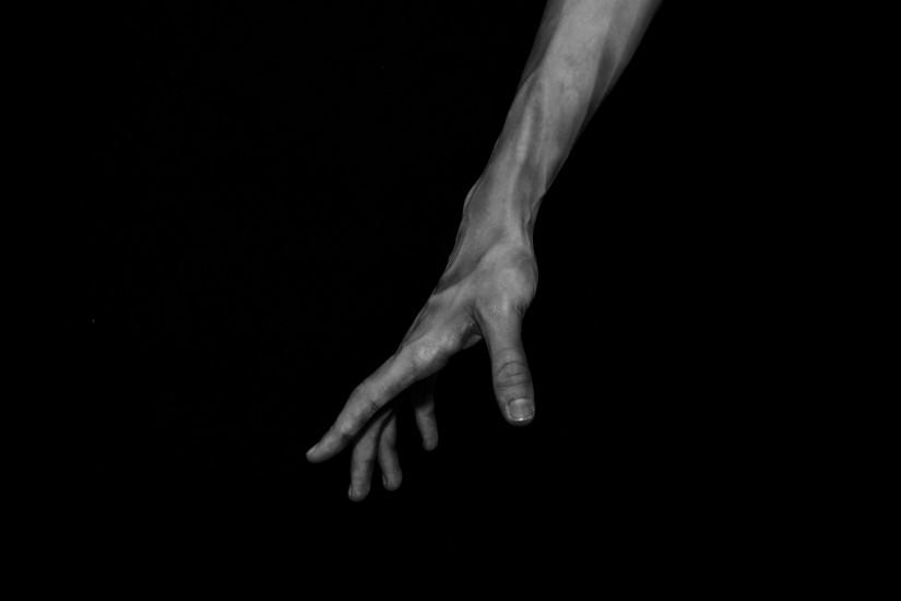 hand reaching down on black background