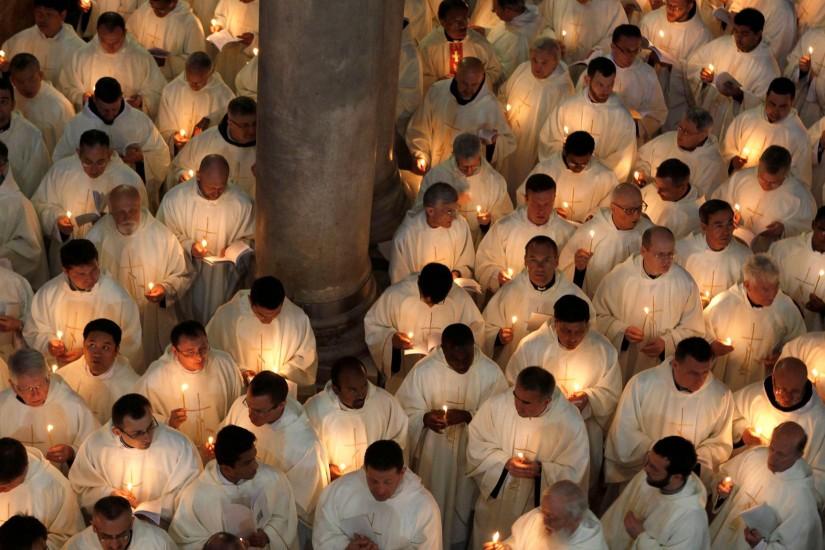 Roman Catholic clergymen hold candles as they circle the Anointing Stone  during the Holy Thursday mass