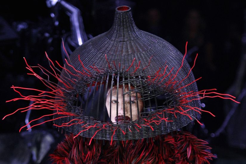 A model wears a demented woven basket on her head by British designer Alexander  McQueen as