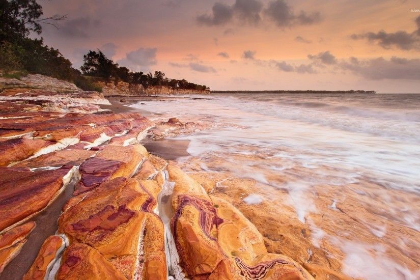 Rusty rocks washed by the foamy ocean waves wallpaper