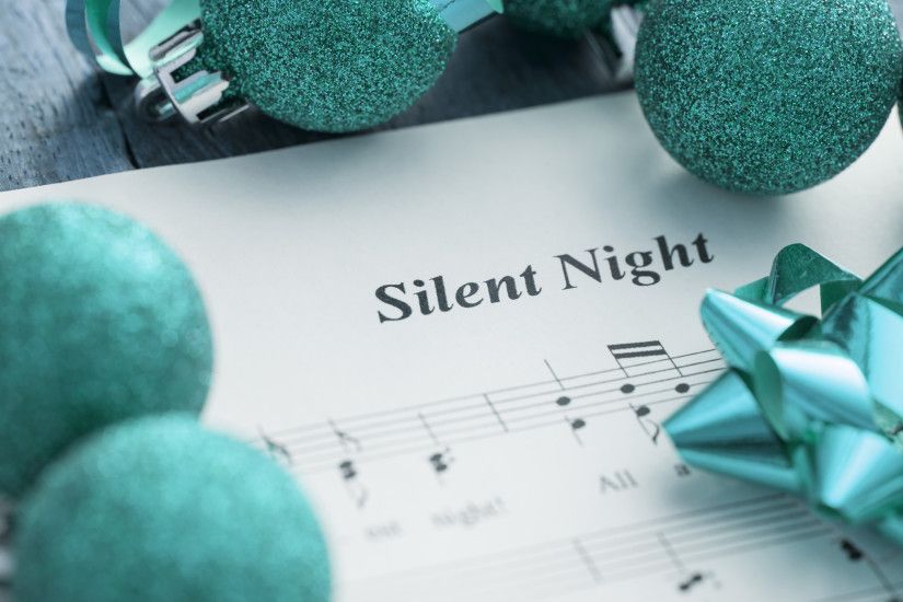 Decorative Christmas carols music background with the score for Silent  Night surrounded by green glitter baubles