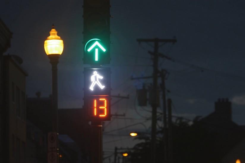 Traffic signal with flashing white pedestrian changing to orange hand with  countdown. Urban background in Ville de Quebec, Quebec, Canada.