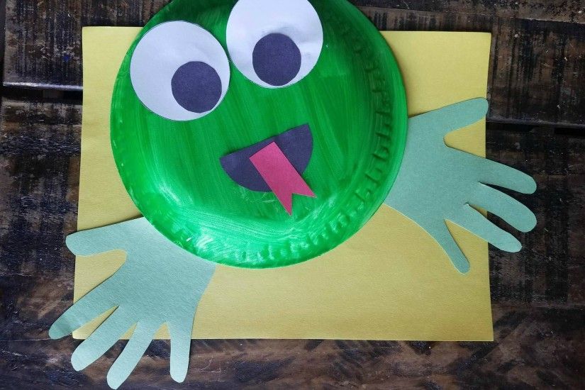 Glue the eyes to the top of your paper plate and assemble the mouth too!  Attach your hand print cutouts to the back side for your froggy's feet!