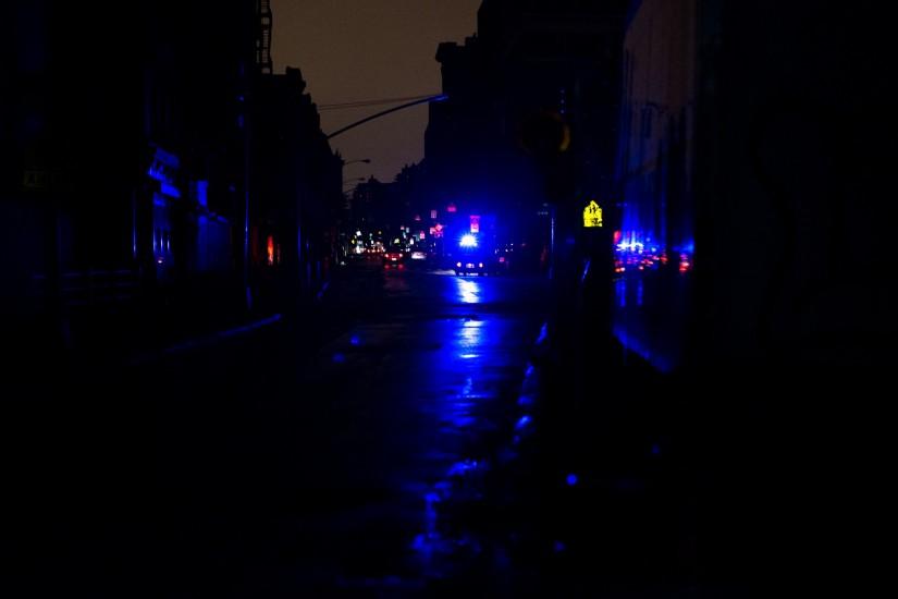 A police car's siren is the only light on a street in Lower Manhattan, which