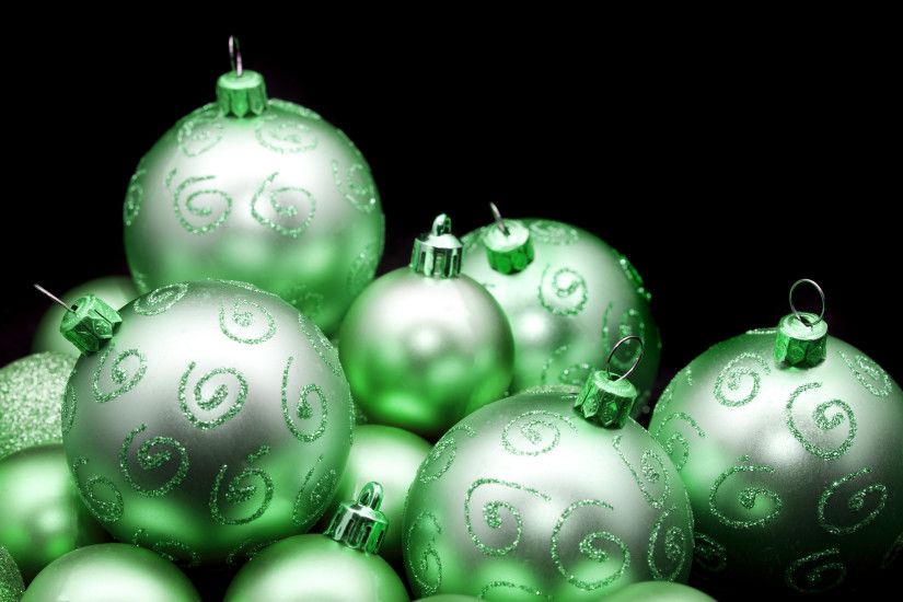Pretty shiny green Christmas baubles with glitter decoration against a dark  background with copyspace for your