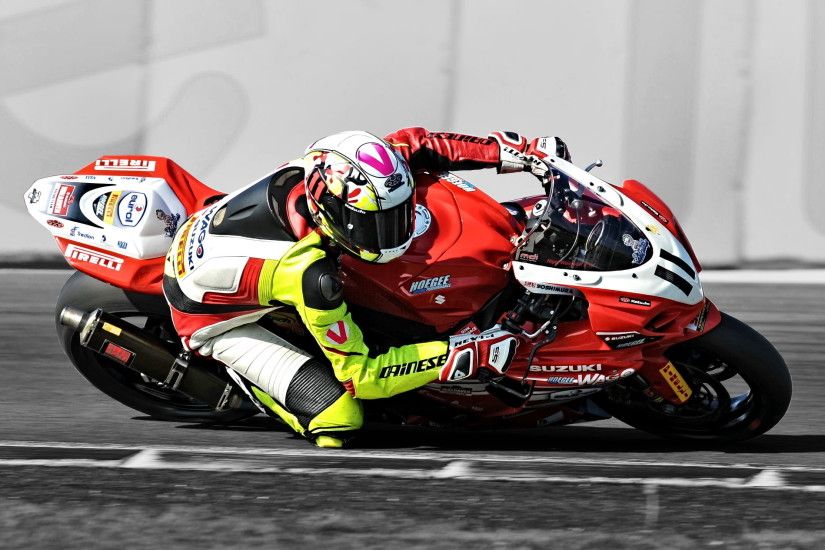 photo of man in motorcycle suit riding on red and white sport bike