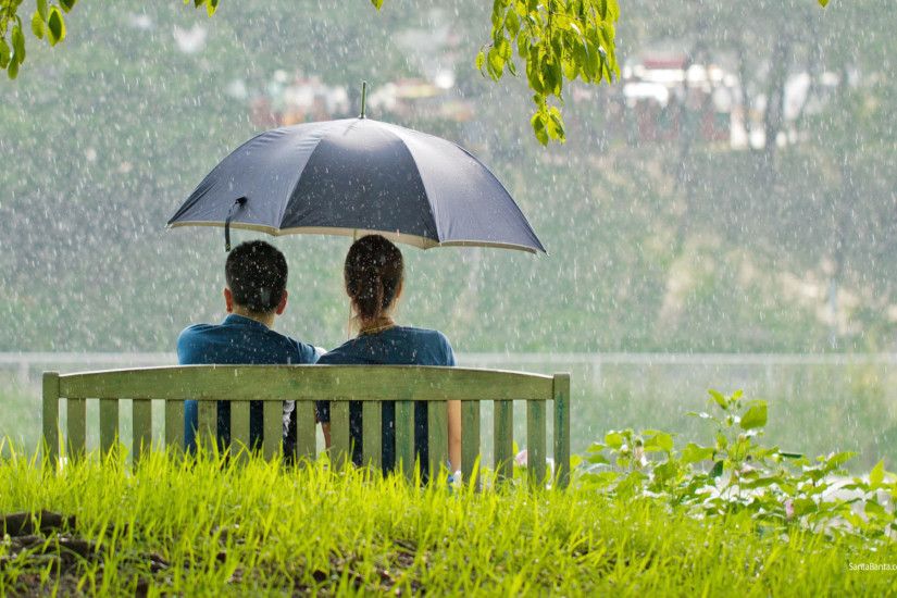 Romantic couple sitting in park while raining