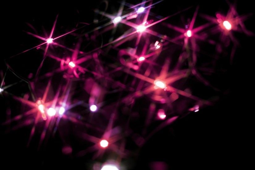 Christmas background of colourful vivid pink starburst lights scattered in  the darkness sparkling and glowing for
