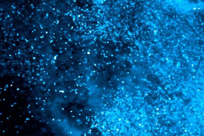 Blue and black particles floating on a dark nebulous background