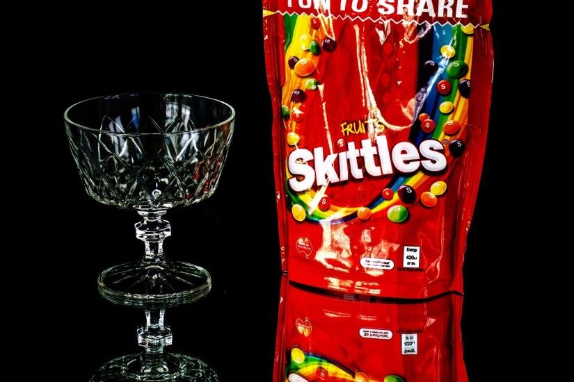 Fruit Skittles pack and clear long-stem drinking glass