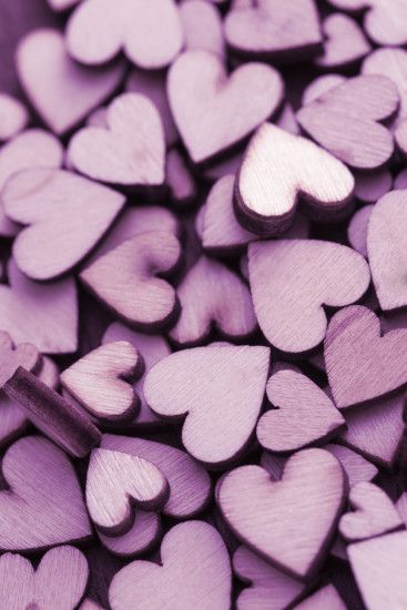Pile of small purple craft wooden hearts cut from plywood, full frame  background concept