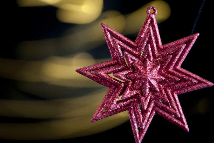 a red coloured glitter star decoration with defuse motion trailed lights in  the background